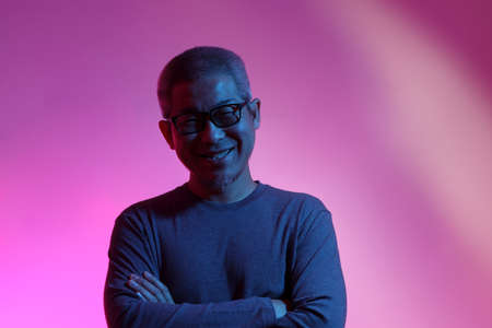 The Asian man with buzz haircut is shot with studio gel lighting.