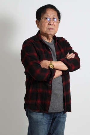 The senior Asin man in in casual clothes on the white background.