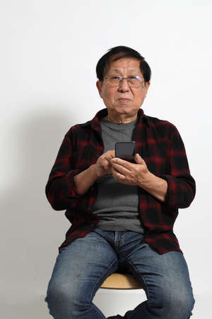 The senior Asin man in in casual clothes on the white background.