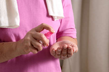The Asian elder female using alcohol spray to avoid virus.の写真素材