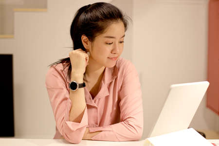 The Asian woman relaxing in the house.