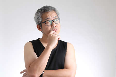 The elder Asian man in sport uniform standing on the white background.