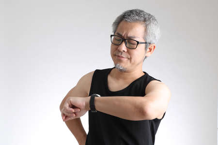 The elder Asian man in sport uniform standing on the white background.