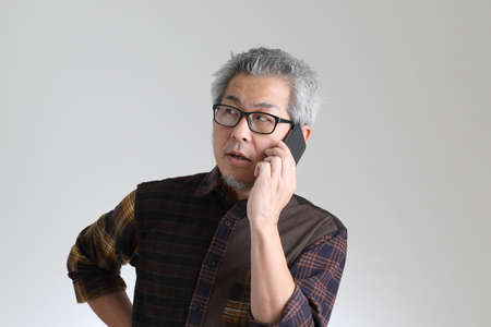 The senior Asian man standing on the white background