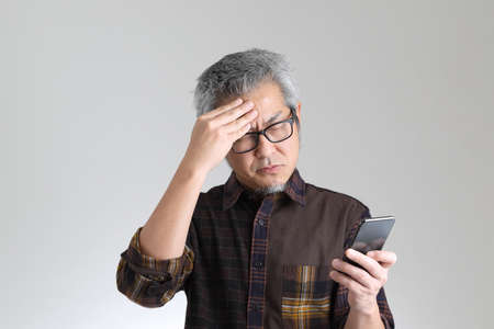 The senior Asian man standing on the white backgroundの写真素材