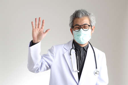The senior Asian physician with mask on the white background.の写真素材