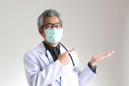 The senior Asian physician with mask on the white background.の写真素材