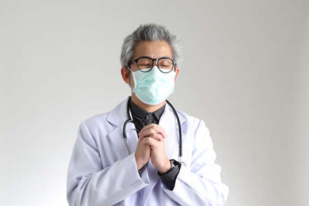 The senior Asian physician with mask on the white background.の写真素材
