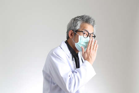 The senior Asian physician with mask on the white background.の写真素材
