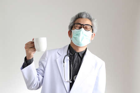 The senior Asian physician with mask on the white background.の写真素材