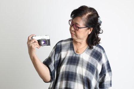 The elder Asian woman standing on the white background.
