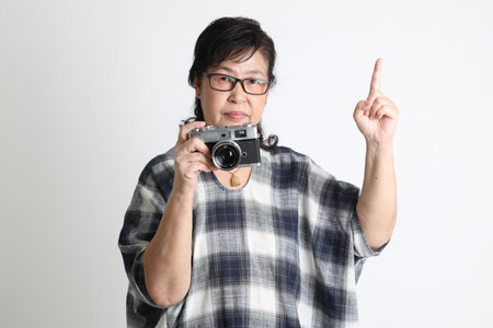 The elder Asian woman standing on the white background.の写真素材