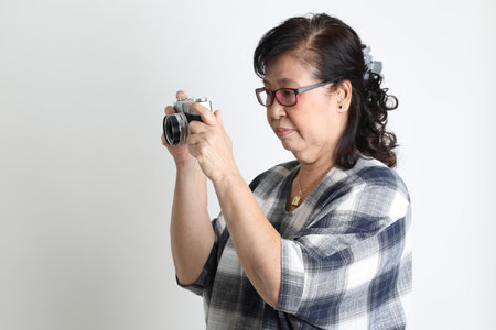 The elder Asian woman standing on the white background.