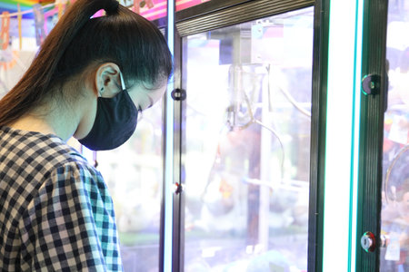 The Asian woman playing crane game to grab a toy.の写真素材