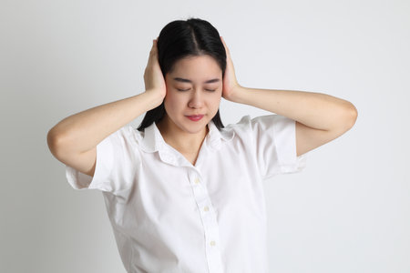 The Asian girl in university uniform standing on the white background.