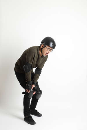 The Asian man with protective gear standing on the white background.