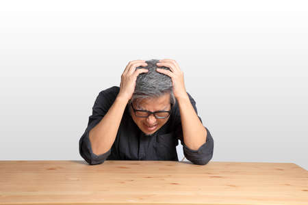 The senior Asian man sitting at the desk.