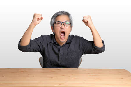 The senior Asian man sitting at the desk.
