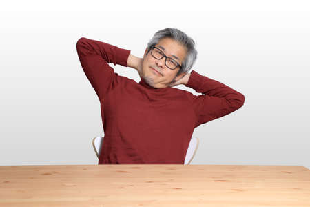 The Senior Asian man sitting at the desk on the white background.