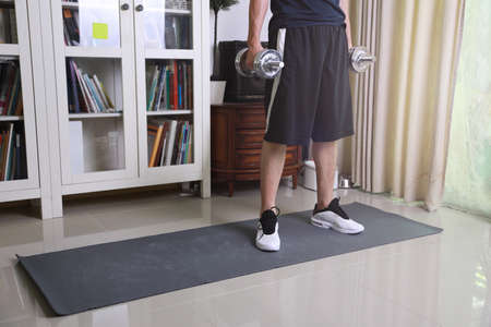 The senior Asian man doing workout in the living room.