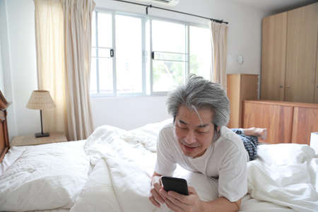 The senior Asian man in the bedroom.