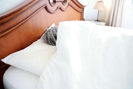 The senior Asian man in the bedroom.