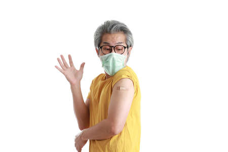 The senior Asian man with mask showing plaster on his shoulder.の写真素材