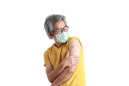 The senior Asian man with mask showing plaster on his shoulder.の写真素材