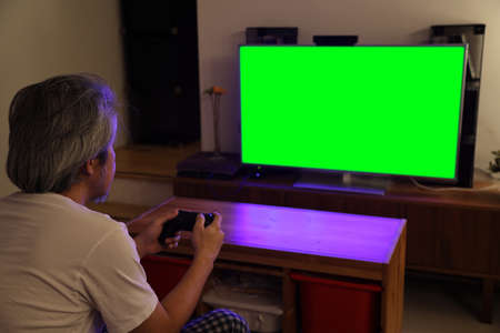 The senior Asian man sitting on the sofa watching television, the camera focus at model.