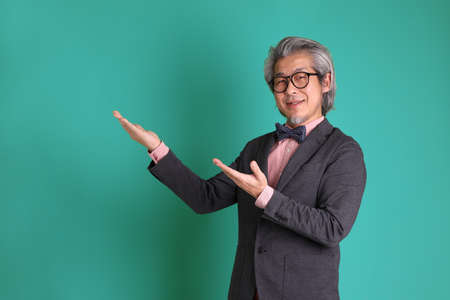 The senior Asian teacher standing on the green background.の写真素材