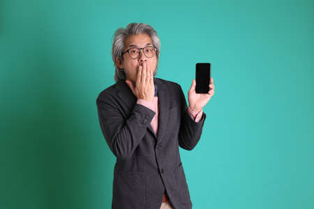 The senior Asian teacher standing on the green background.の写真素材