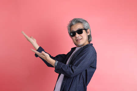 The Asian man standing on the pink background.