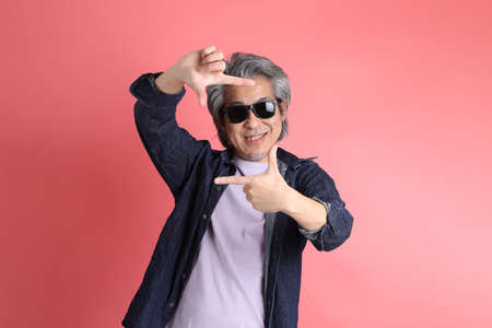 The Asian man standing on the pink background.の写真素材