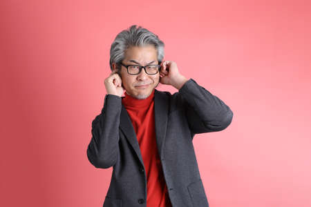 The Asian man standing on the pink background.の写真素材