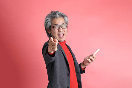 The Asian man standing on the pink background.
