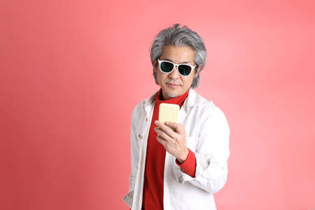 The Asian man standing on the pink background.
