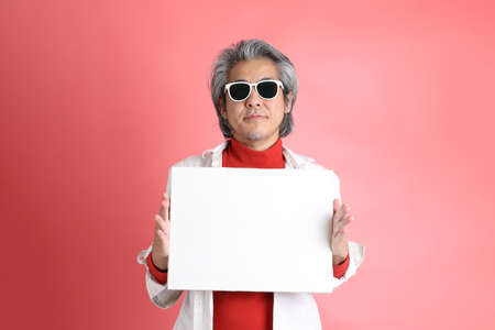 The Asian man standing on the pink background.