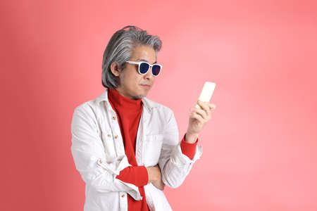 The Asian man standing on the pink background.の写真素材