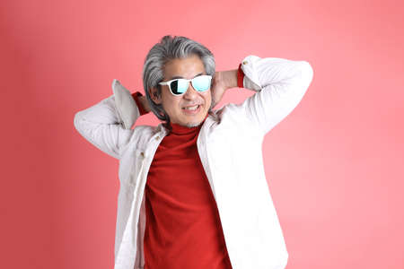 The Asian man standing on the pink background.