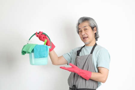 The senior Asian housekeeper standing on the white background.