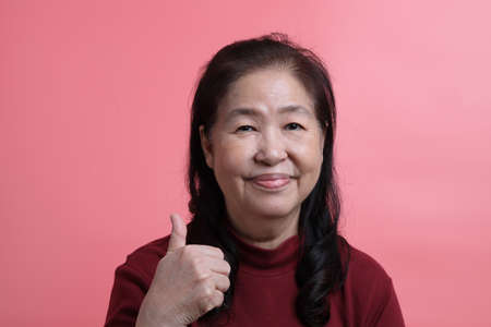 The senior Asian woman portrait with no retouched skin in the pink background.の写真素材