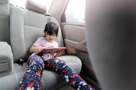 The Asian kid using mobile device in the car.の写真素材