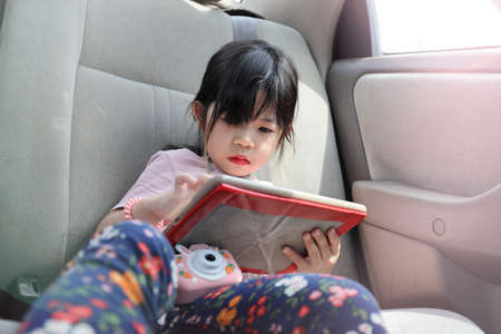 The Asian kid using mobile device in the car.