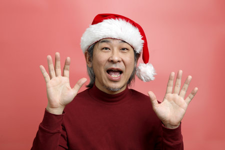 The Asian man portrait with santa claus hat on the pink background.の写真素材