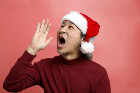 The Asian man portrait with santa claus hat on the pink background.
