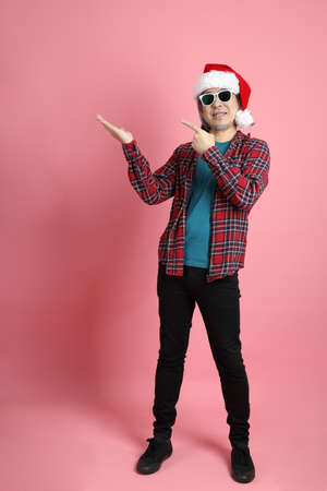The senior Asian man with Christmas hat standing on the pink background.の写真素材