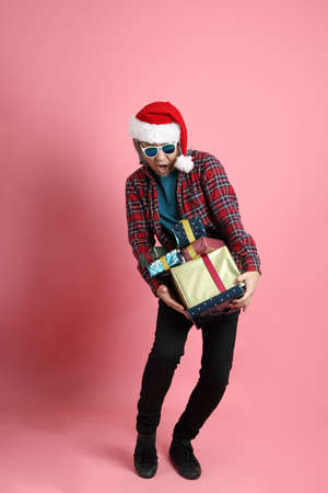 The senior Asian man with Christmas hat standing on the pink background.の写真素材