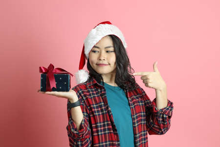 The Asian woman with santa hat standing on the pink background.の写真素材