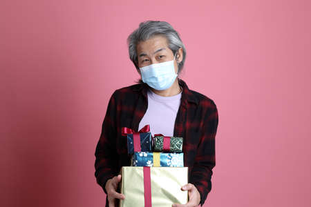 The senior Asian man portrait on the pink background.