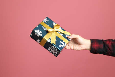 The Asian man hand holding present to give for someone on the pink background.